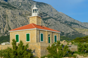 Fototapeta na wymiar Lighthouse on Makarska riviera beach in Makarska, Croatia on June 17, 2019.