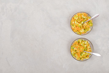 Fresh cabbage salad with carrots in a bowl on a light background top view