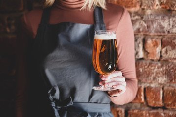 brewer in apron holds glass of beer