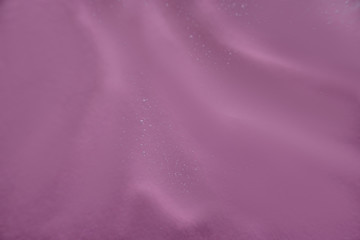 Abstract texture. Liquid gel cosmetics with little bubbles. Pink background. Face cream. Close-up. Cosmetics product.