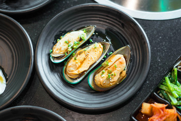 Raw mussels on black plate.