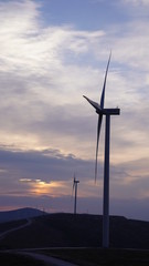 Wind turbines are generating power at sunset background. The concept of clean and renewable energy.