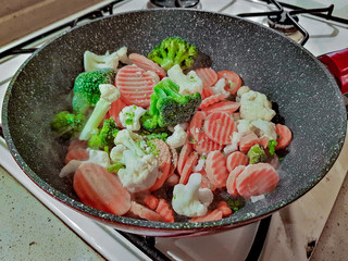 Vegetables are fried in a pan with seed oil on a gas stove
