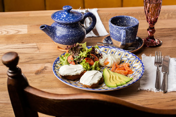 Poached eggs with salmon and avocado on sourdough toast isolated on wooden background. Homemade food. Tasty breakfast. Selective focus. Top view.