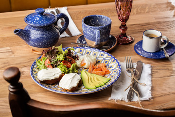 Poached eggs with salmon and avocado on sourdough toast isolated on wooden background. Homemade food. Tasty breakfast. Selective focus. Top view.