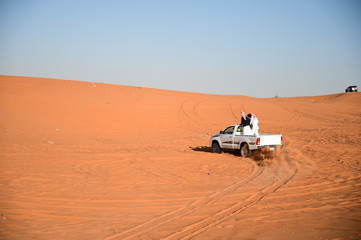 Group of people enjoy drifting their pick-up 4 wheels drive vehicle in the red sand desert in Saudi Arabia.