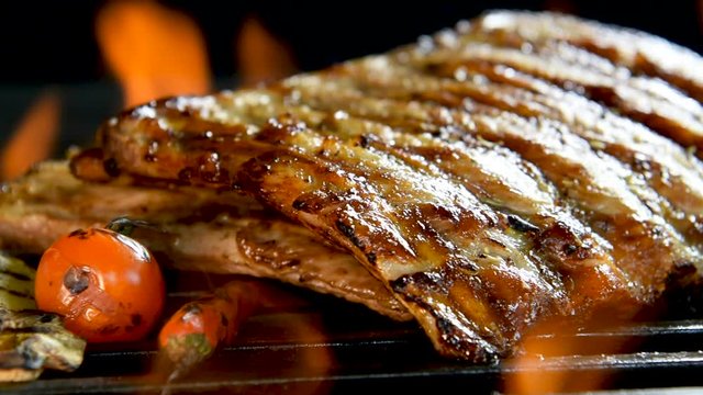 Grilled pork ribs on the flaming grill .
