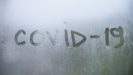 Worldwide coronavirus quarantine and insulation. The inscription covid 19 on the foggy rainy window.