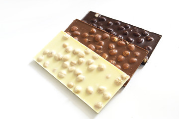 black, milk and white chocolate with nuts on a white background