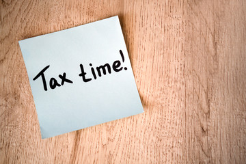 Tax time concept on blue note sticker on wooden background