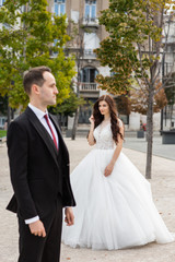 Bride and groom dancing in the old town street. Wedding couple walks in Budapest near Parliament House. Caucasian happy romantic young couple celebrating their marriage. Wedding and love concept.