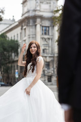 Naklejka premium Bride in the old town street. Wedding walks in Budapest near Parliament House. Caucasian happy romantic young woman celebrating her marriage. Wedding and love concept.