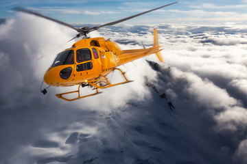 Yellow Helicopter flying over the Snow Covered Alpine Mountains during a sunny winter day. Aerial...