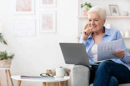 Confident senior woman working with laptop and papers at home
