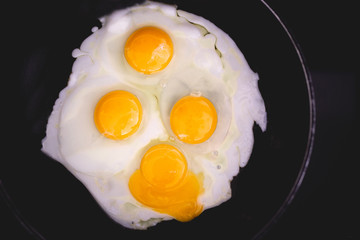 Fried eggs in frying pan. Four eggs. Making breakfast for family. Family weekend breakfast. Quick easy brunch breakfast. Over medium fried eggs. Egg yolk, egg whites. Black stove top. Broken egg yolk