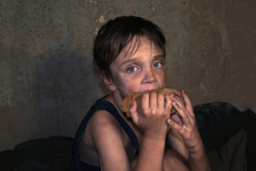 Child homeless, beggar eat a piece of black bread (concept of war, poverty, crisis)