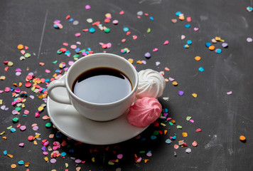 pink and white meringue with confetti and cup of coffee