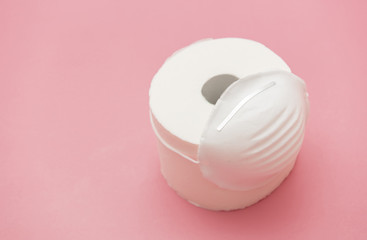 Toilet paper and face mask on pink color background