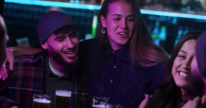 Multi-ethnic group of friends drinking beer inside trendy bar