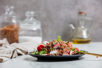 boiled buckwheat with radish and fork on a plate, vegetarian dish