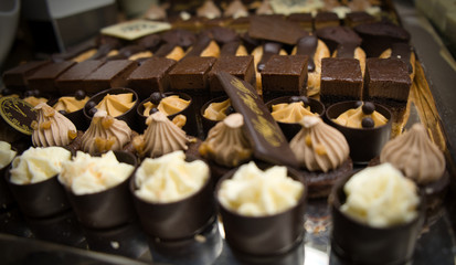 Close up of dessert buffet on new year. Small pieces of chocolate cake and cream cakes. Petit four.