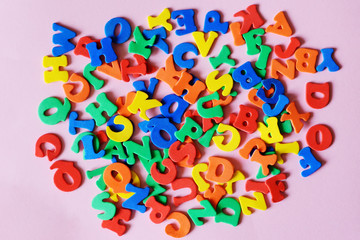 multicolored letters of the English alphabet mixed on a pink background. The concept of the Junior school, ABC