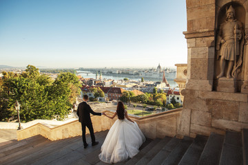 Bride and groom hugging in the old town street. Wedding couple walking on the Fisherman's Bastion, Budapest, Hungary. Happy romantic young couple celebrating their marriage. Wedding and love concept.