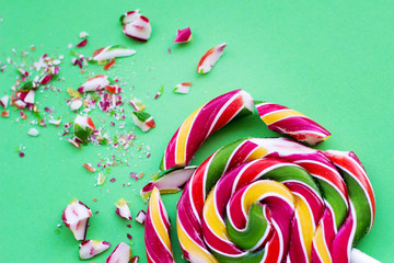 Broken in pieces candy on a stick. Smashed lollipop on green background
