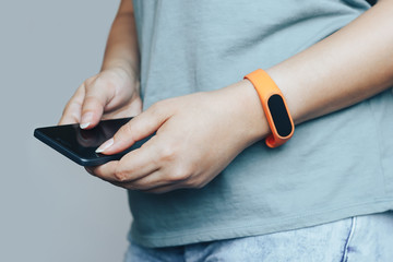 Woman with fitness tracker on her wrist is holding a phone. - 345209067