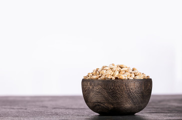 Hordeum vulgare - Pearl barley in wooden bowl on white background