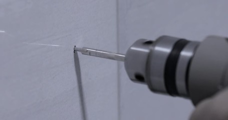 Closeup of a drill bit drilling a hole in a wall	