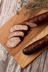 Industrial manufacture of sausages. Smoked sausage on a wooden rustic table with addition of fresh aromatic herbs and spices, natural product from organic farm, produced by traditional methods.