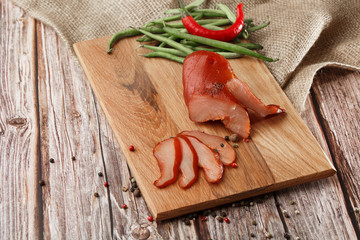 Meat smoked jerky - raw meat sausage meat. Close up view on tasty sliced Chicken basturma on parchment on a wooden board on a wooden background in a composition with spices. Beer snack. Pastirma