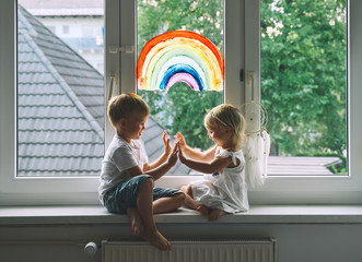 Little children on background of painting rainbow on window