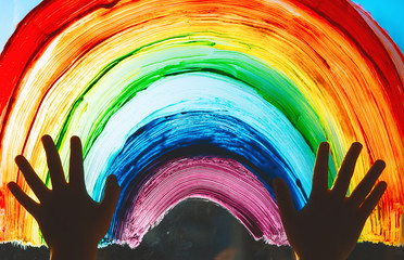 Child hands touch painting rainbow on window. © nataliaderiabina
