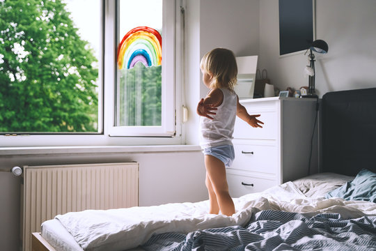 Cute little girl having fun time jumping on bed at home.