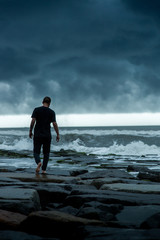 man walking on stormy coast