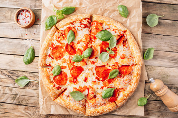 Pepperoni pizza with basil on a rustic background. Top view