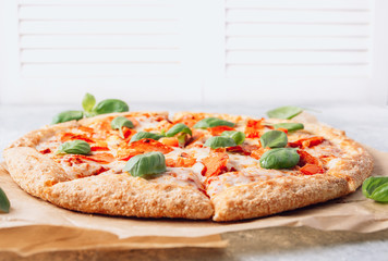 Pepperoni pizza with basil on a rustic background.