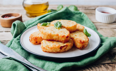 Hash brown or potato pancakes on plate with catsup on wooden rustic background with green napkin.