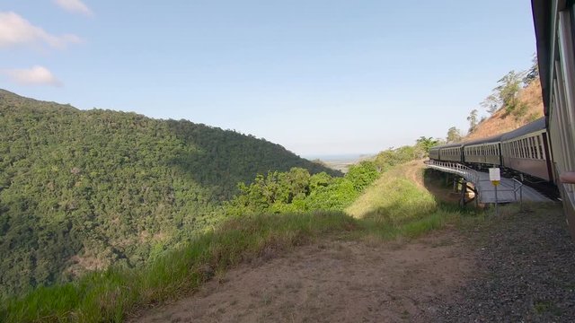Kuranda Scenic Railway Train. Tourist train journey across rainforest and jungles in Cairns Australia. View of train, train tracks, passenger seats, interior, skyrail, bridge, mountains and landscape.
