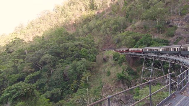 Kuranda Scenic Railway Train. Tourist train journey across rainforest and jungles in Cairns Australia. View of train, train tracks, passenger seats, interior, skyrail, bridge, mountains and landscape.