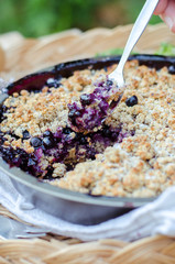 Cake with fork. Closeup image of freshly baked cake with blueberries and crumble during sunny, warm day. 
