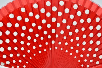 detalle de abanico de madera abierto, pintado de rojo con lunares blancos	