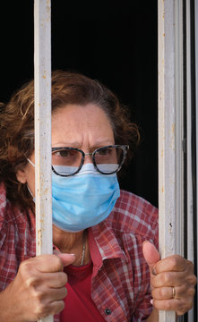 adult woman with a face mask looking out of the windows