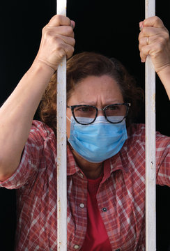 adult woman with a face mask looking out of the windows