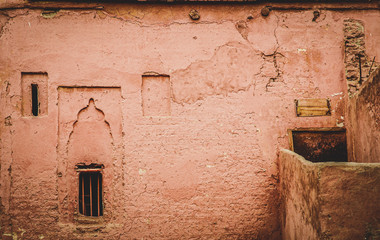 Worn and dirty pink ochre painted adobe wall