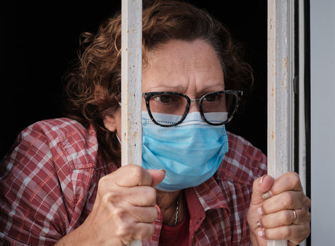 adult woman with a face mask looking out of the windows