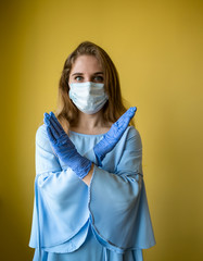 a young beautiful woman with long hair wearing a medical mask and protective disposable gloves on a...