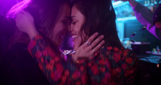 Lesbian couple kissing inside bar, throwing confetti